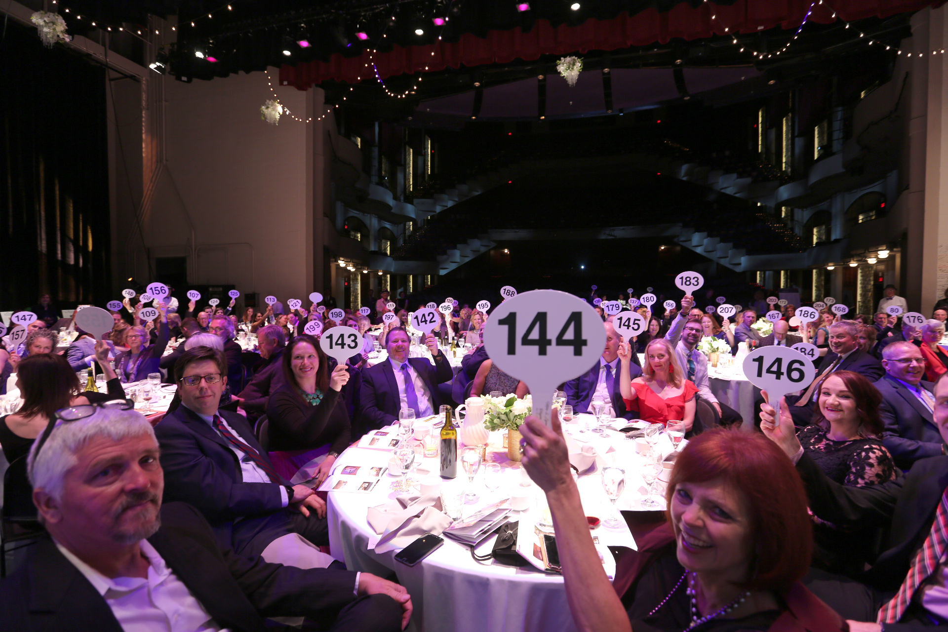Auction guests raising bid paddles at a charity gala